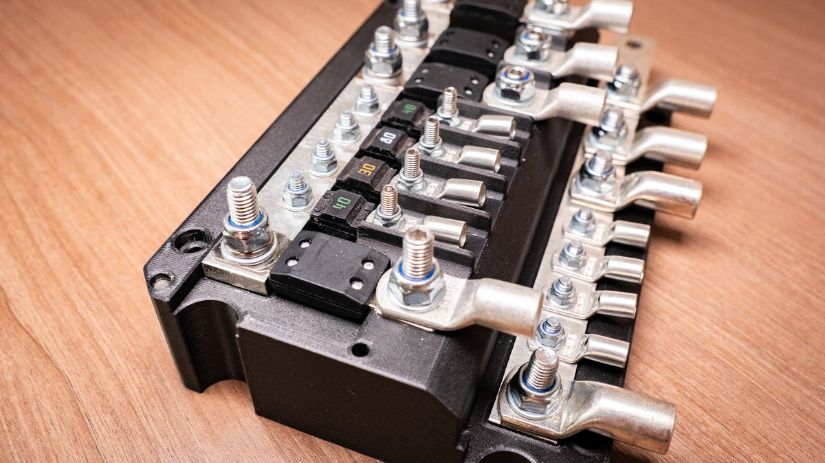 Close-up of the Falcon 8-Way 12V Power Distribution Block showing bolted MEGA and MIDI fuses and cable lugs