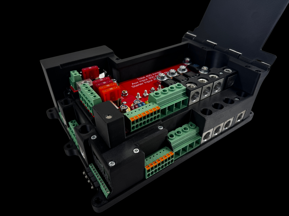 Close-up inside the Giga Power Hub 12V power distribution system, showing blade fuses, green connectors and metal terminal blocks