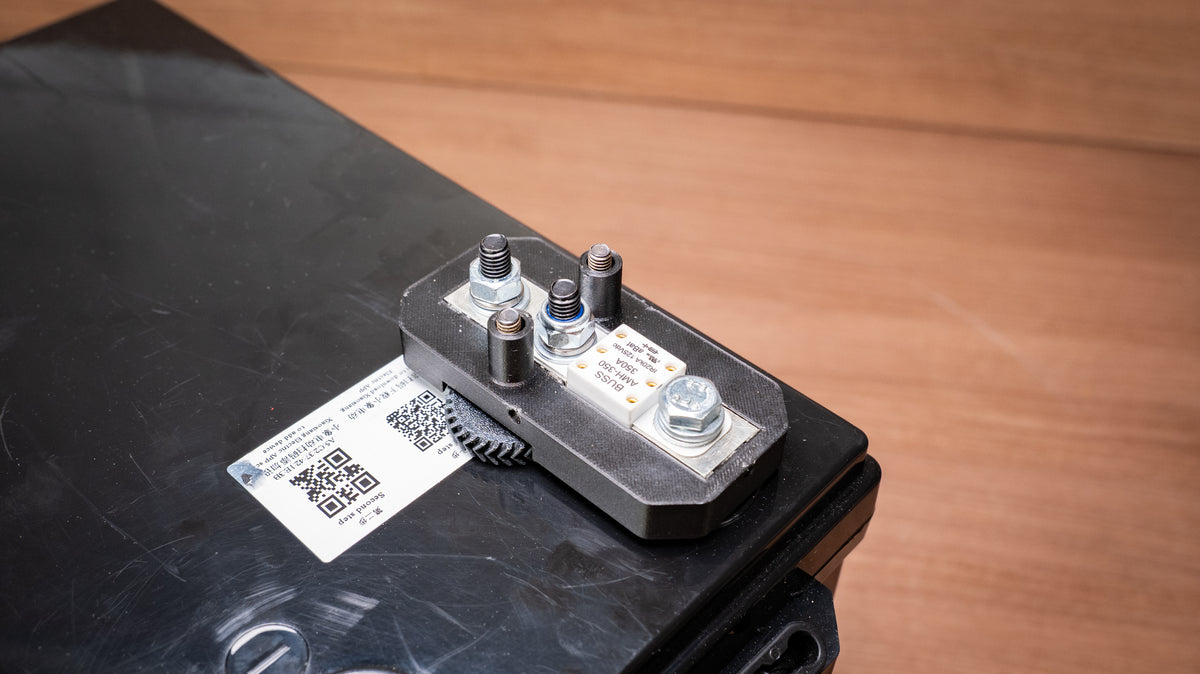Lithium battery fuse and holder mounted on a battery with the cover removed and terminals exposed